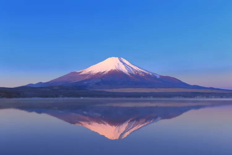 Mount Fuji reflected in a still lake at dawn