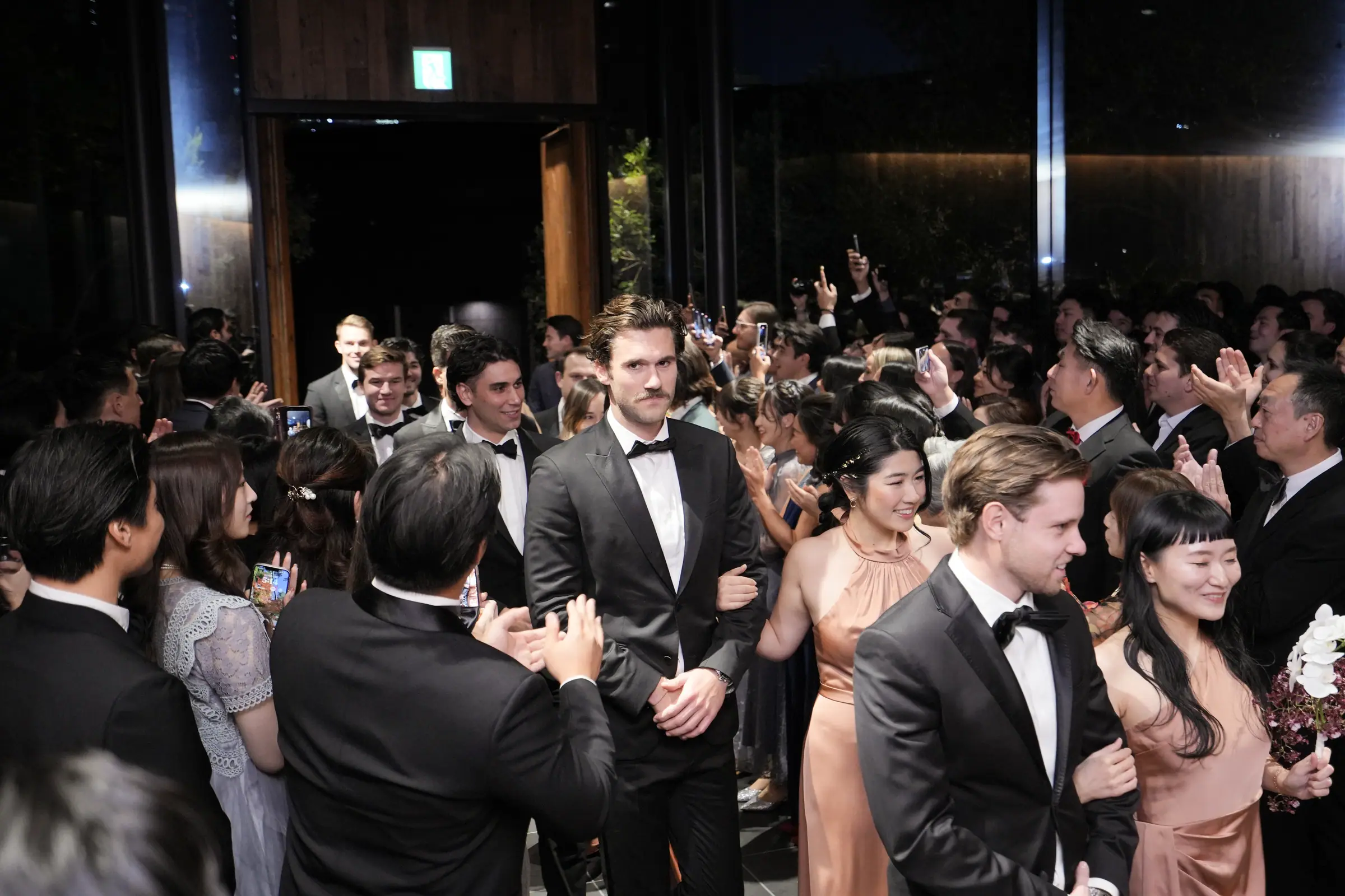 A groom entering the reception through a crowd of guests