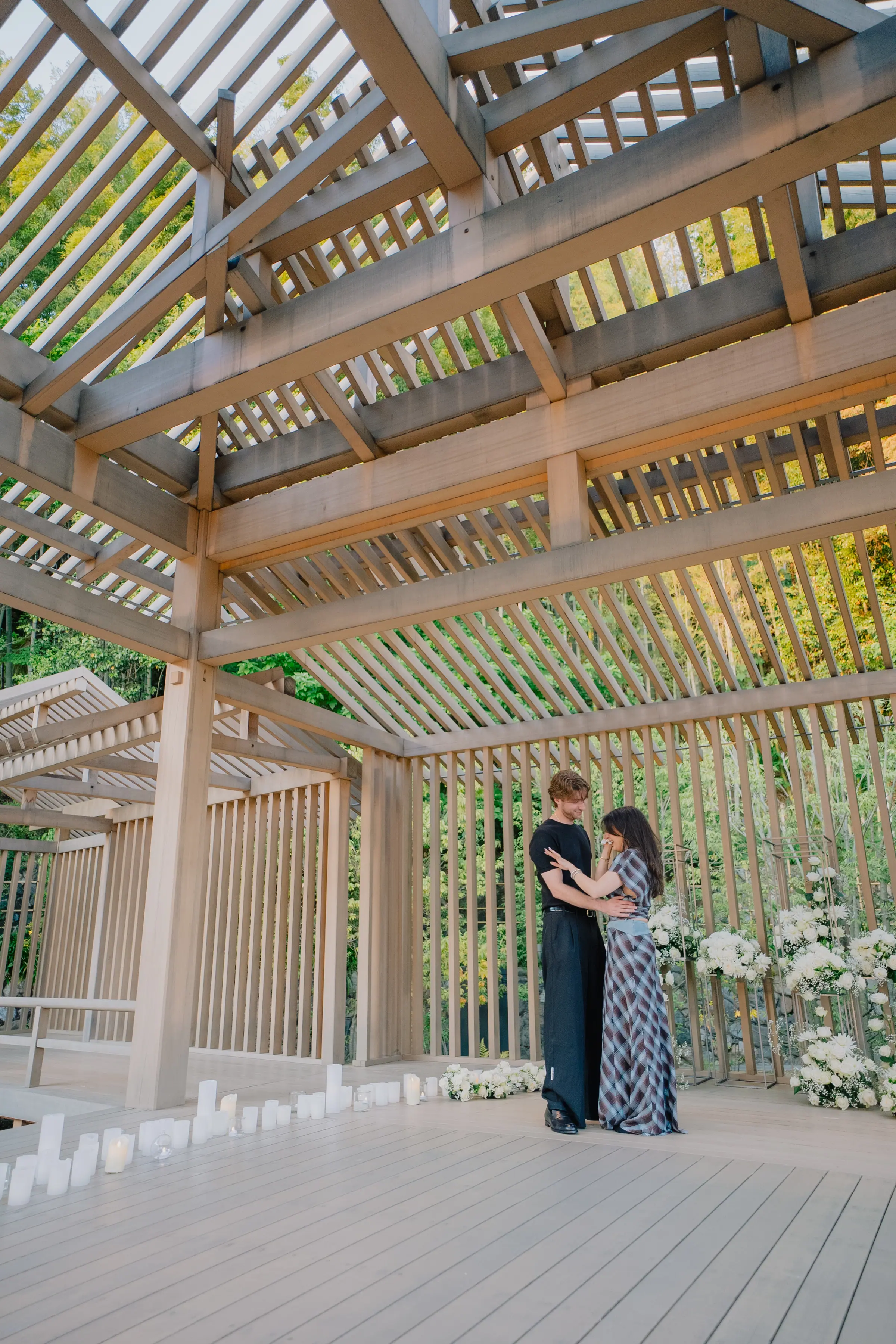 A couple embracing among candles and white flowers
