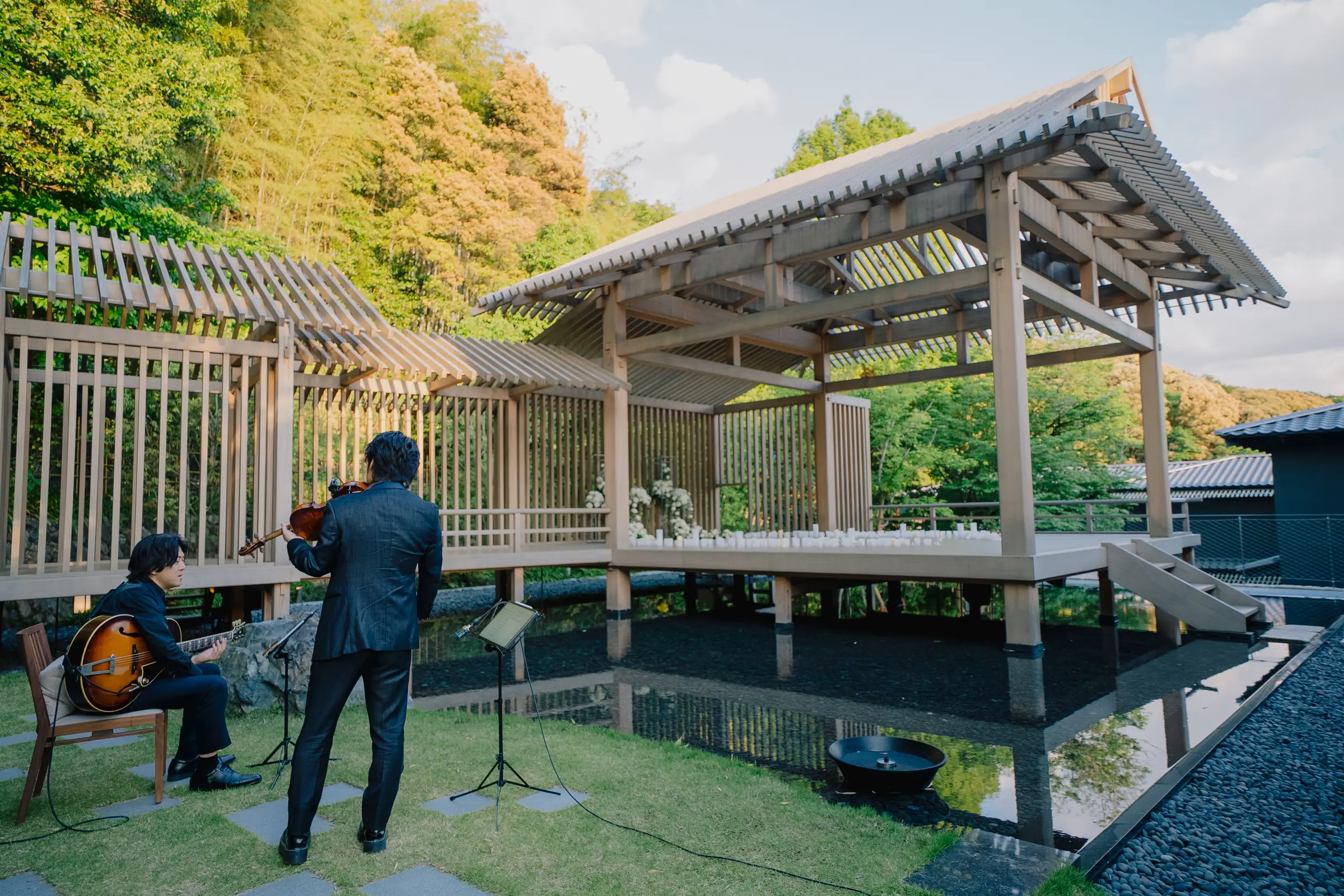 Musicians playing beside a cedar pavilion over water