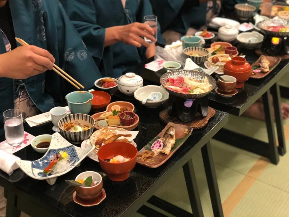 Multi-course kaiseki meal laid out on low lacquer tables for guests seated on tatami at a Japanese wedding celebration